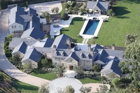 An aerial view of Joel Osteen's grand residence, surrounded by lush greenery and featuring a sparkling blue pool. The house stands as a tranquil oasis amidst nature, showcasing its elegance and serenity.