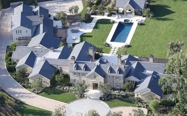 An aerial view of Joel Osteen's grand residence, surrounded by lush greenery and featuring a sparkling blue pool. The house stands as a tranquil oasis amidst nature, showcasing its elegance and serenity.