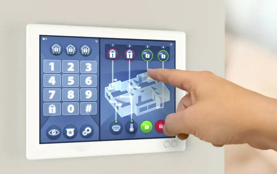 Hand interacting with a smart security system touchscreen, displaying a home layout and control panel for automated security features.