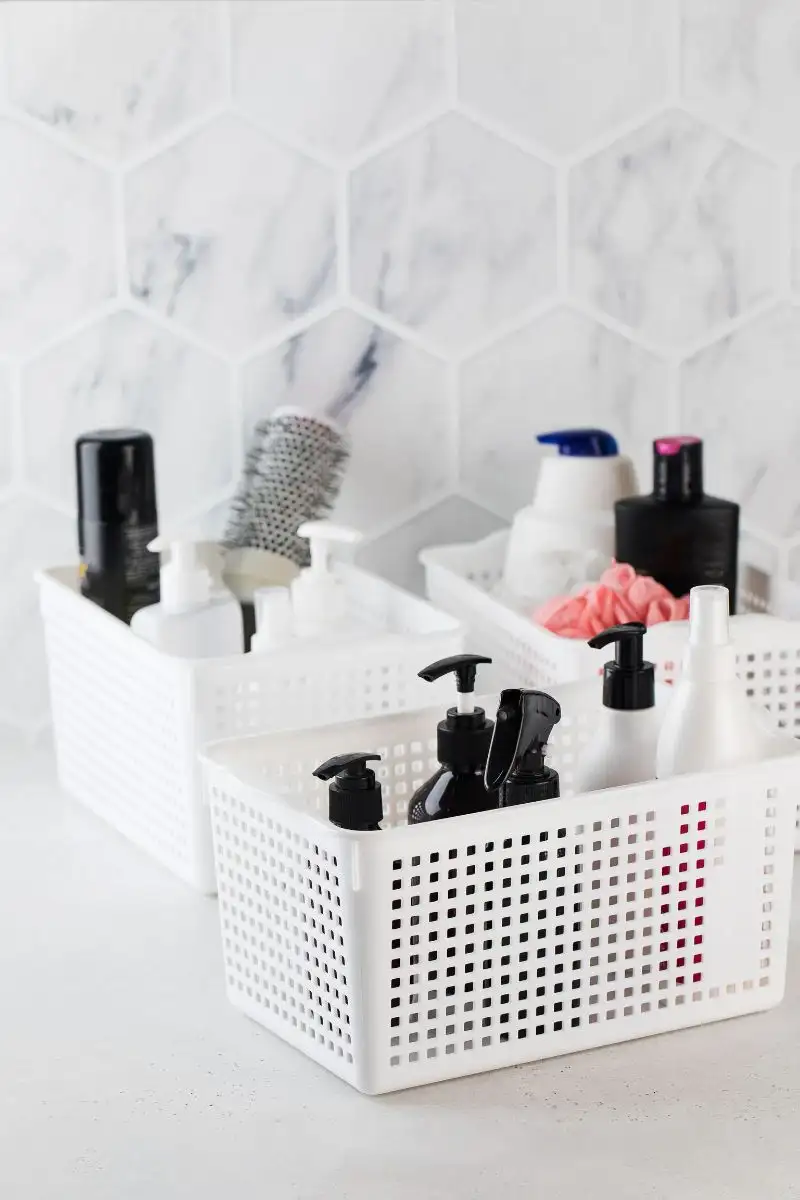 White plastic baskets on a bathroom countertop holding various hair and skincare products, illustrating a solution for insufficient storage in bathrooms.