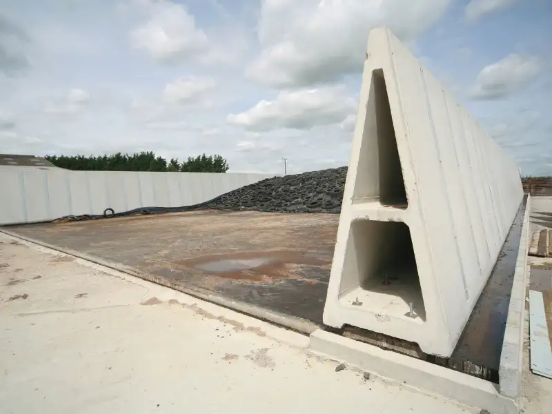 Precast concrete silage clamps with angular design on an outdoor site under a cloudy sky.