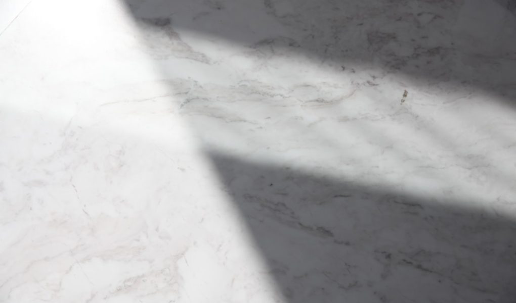 a white marble counter top with a long shadow