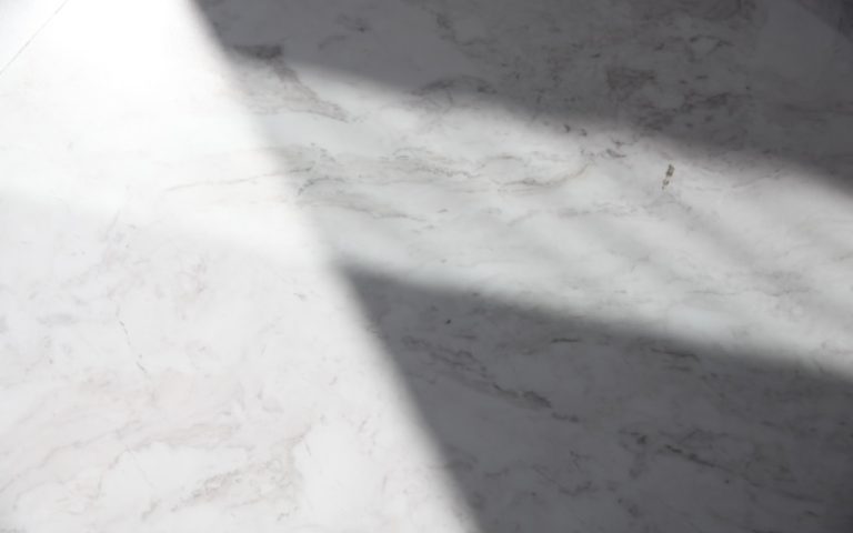 a white marble counter top with a long shadow