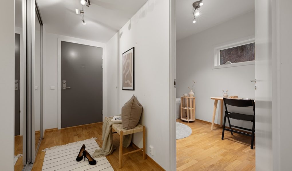 A hallway with a white wall and wooden floors