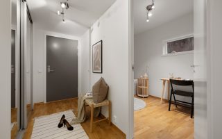 A hallway with a white wall and wooden floors