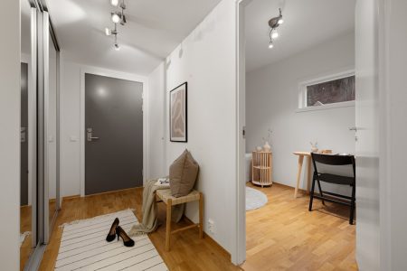 A hallway with a white wall and wooden floors