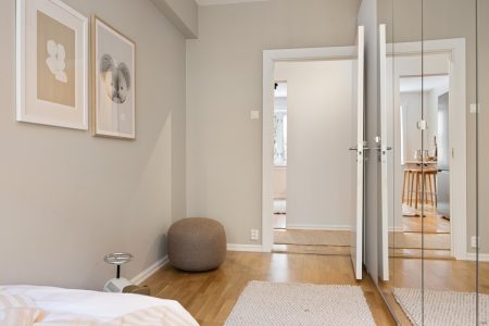 A bedroom with a bed, mirror, and pictures on the wall