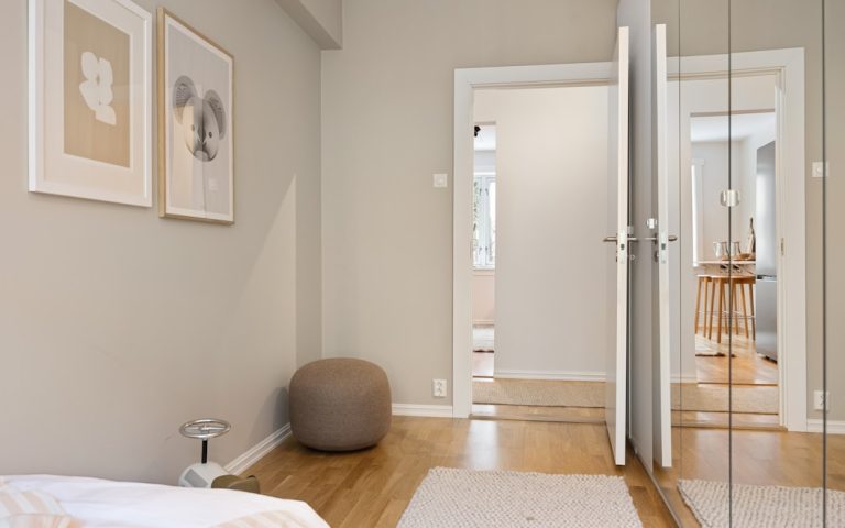 A bedroom with a bed, mirror, and pictures on the wall