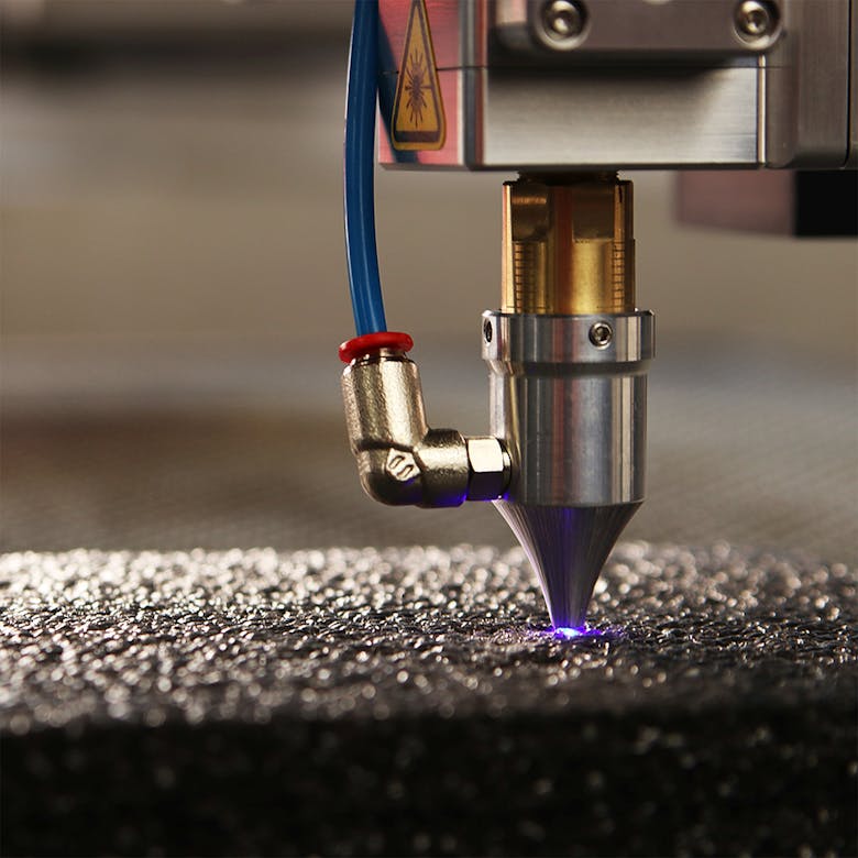 Close-up of a high-precision laser engraver focusing on a textured surface.