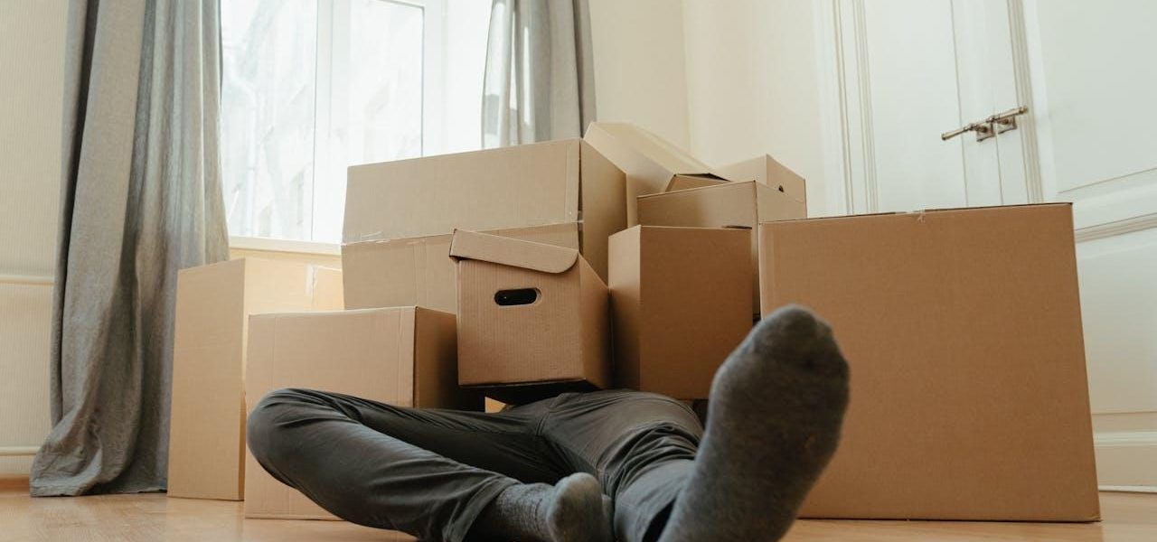 Person in black pants underneath a pile of cardboard boxes