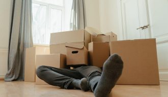 Person in black pants underneath a pile of cardboard boxes