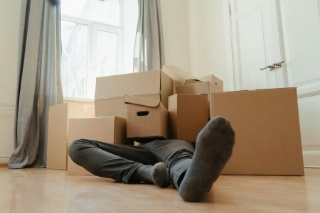 Person in black pants underneath a pile of cardboard boxes