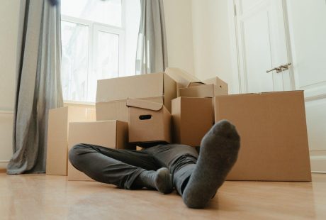 Person in black pants underneath a pile of cardboard boxes
