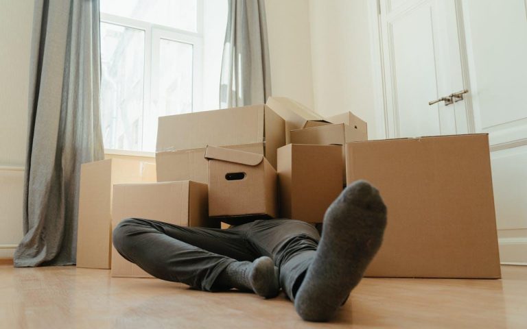 Person in black pants underneath a pile of cardboard boxes