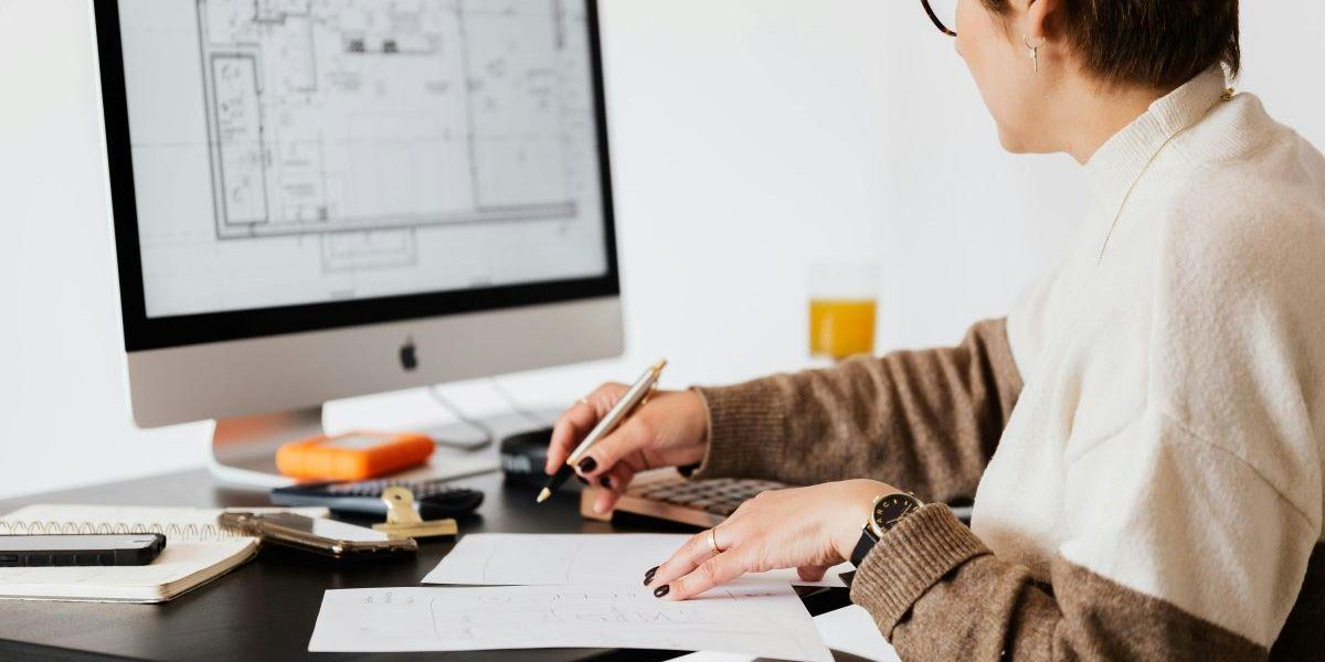 A person working on a computer blueprint to design a floor plan.