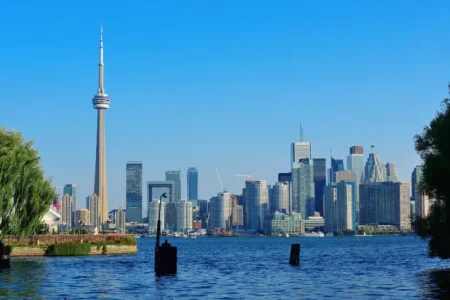 Toronto skyline with the CN Tower and modern skyscrapers viewed across Lake Ontario on a clear sunny day.