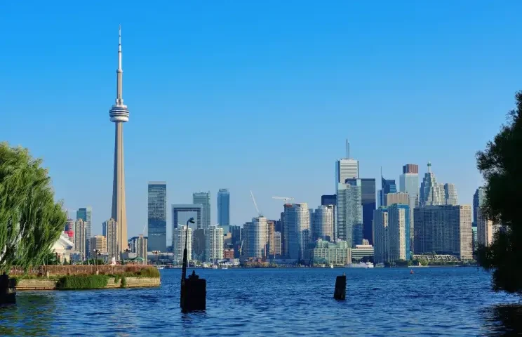 Toronto skyline with the CN Tower and modern skyscrapers viewed across Lake Ontario on a clear sunny day.