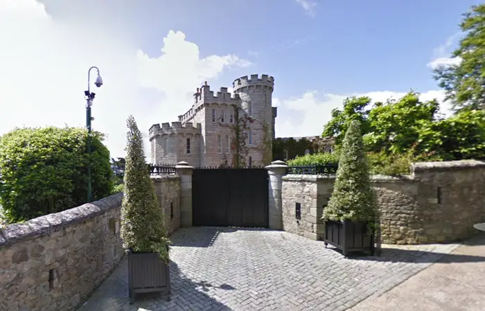 Front entrance of Manderley Castle in Killiney, Dublin, with stone walls, turreted towers, and secure gated driveway.