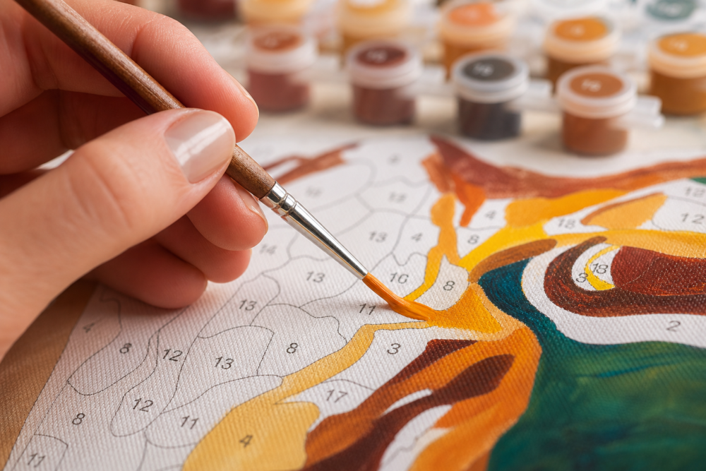 Close up view of hand painting a custom canvas using a fine wooden brush
